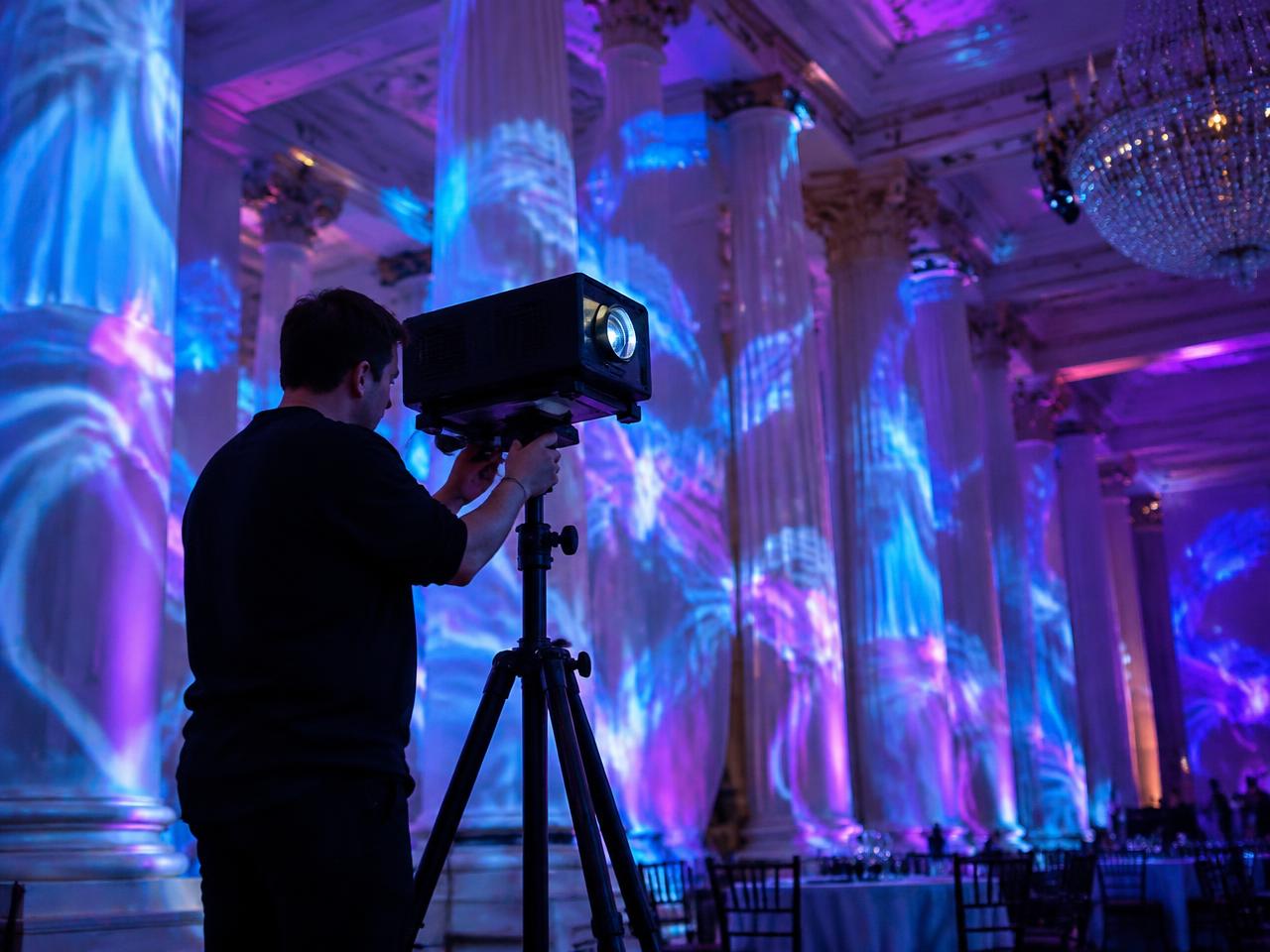 Technician aligning a projector for projection mapping on ballroom columns